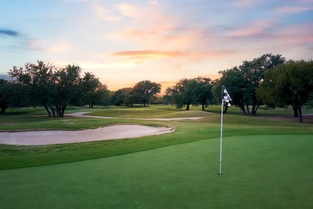 view of property's community featuring view of golf course and a yard