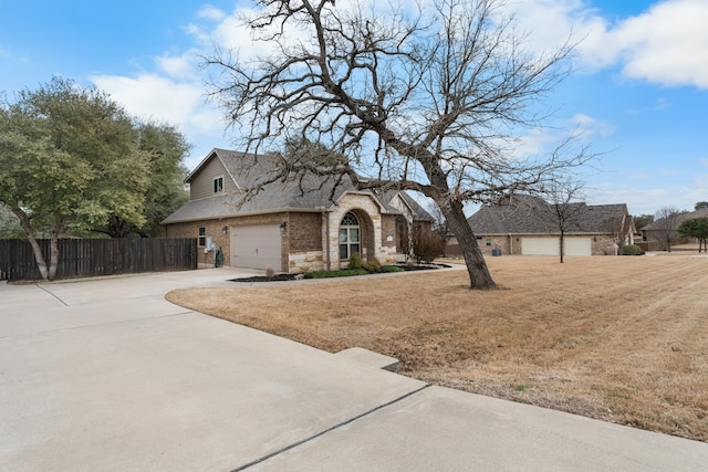 view of front of property with brick siding, a shingled roof, concrete driveway, fence, and a front lawn