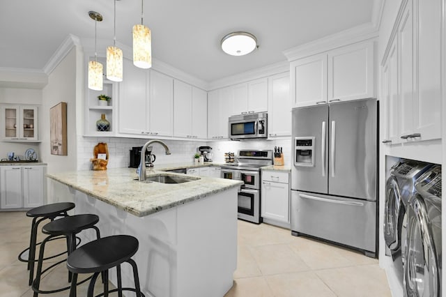 kitchen with crown molding, stainless steel appliances, a sink, independent washer and dryer, and a peninsula