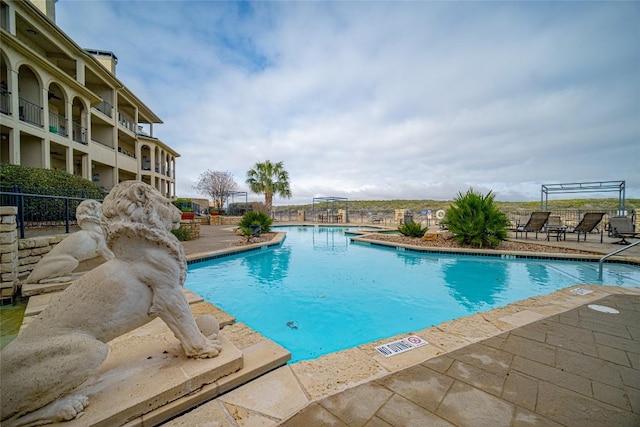 community pool featuring fence and a patio