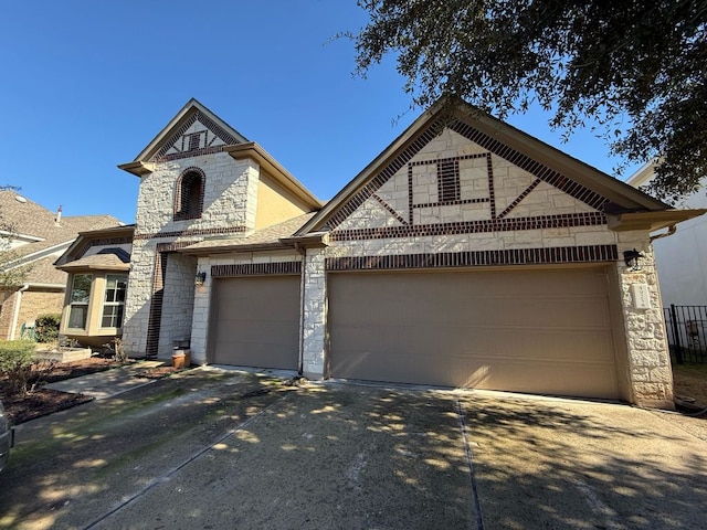 french country style house with an attached garage, concrete driveway, and stone siding