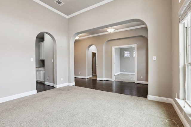 empty room with arched walkways, dark colored carpet, and visible vents