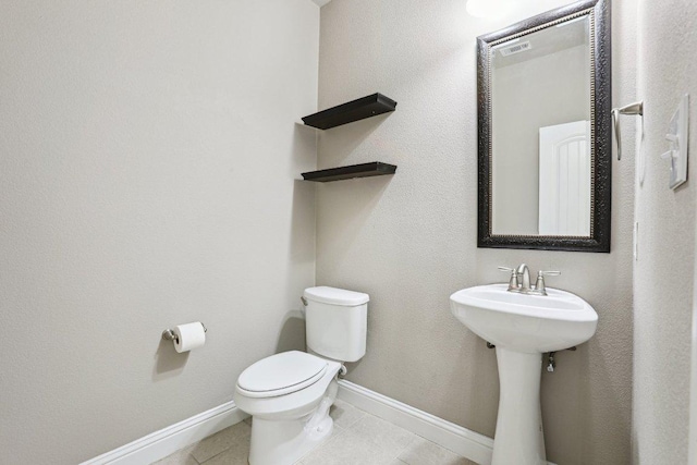 bathroom with tile patterned flooring, baseboards, and toilet