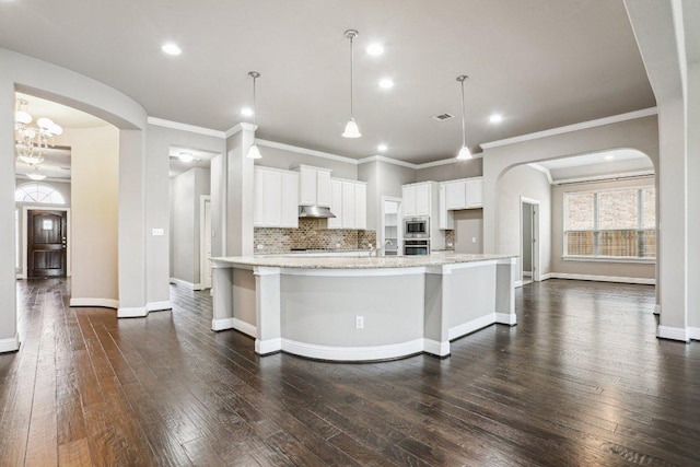 kitchen with baseboards, decorative backsplash, dark wood-style flooring, stainless steel appliances, and under cabinet range hood