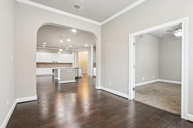 unfurnished living room featuring arched walkways, dark wood-style floors, visible vents, and crown molding