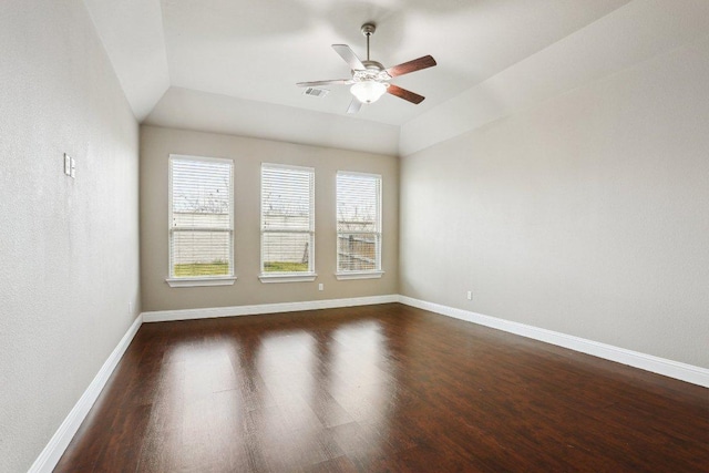 empty room with dark wood finished floors, lofted ceiling, visible vents, a ceiling fan, and baseboards