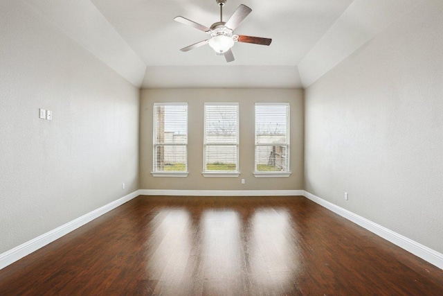 empty room featuring ceiling fan, dark wood-type flooring, vaulted ceiling, and baseboards