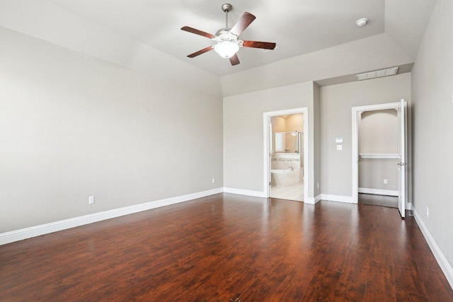 unfurnished bedroom featuring visible vents, connected bathroom, vaulted ceiling, wood finished floors, and baseboards