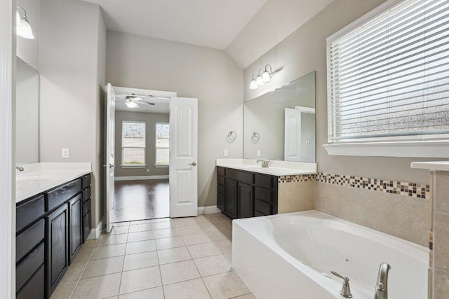 bathroom with a garden tub, tile patterned flooring, two vanities, and a sink