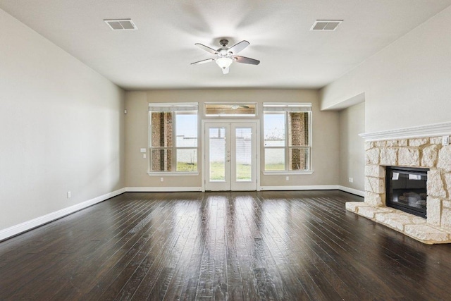 unfurnished living room with french doors, a stone fireplace, dark wood-style flooring, and visible vents