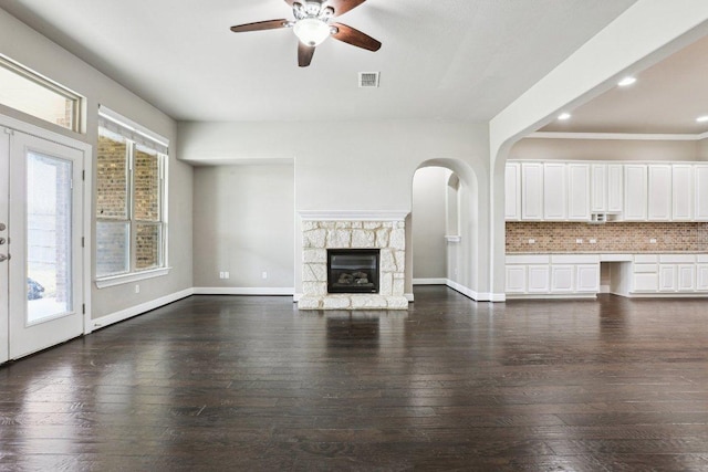 unfurnished living room featuring a healthy amount of sunlight, visible vents, and dark wood-style flooring