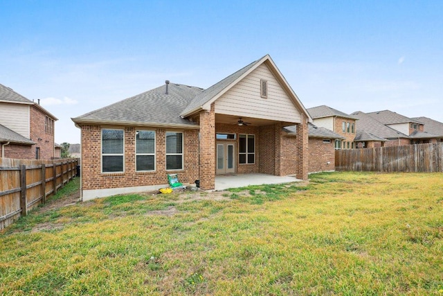 back of property with a lawn, a patio, a ceiling fan, a fenced backyard, and brick siding