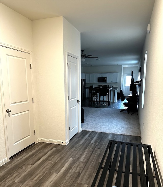 corridor with baseboards and dark wood finished floors