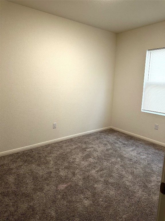 carpeted empty room featuring baseboards