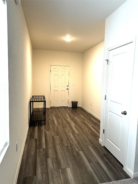 hallway with dark wood-style flooring and baseboards