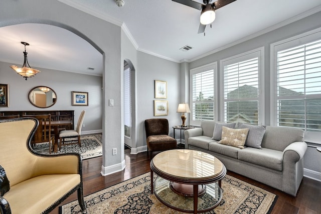 living room featuring arched walkways, dark wood finished floors, visible vents, ornamental molding, and baseboards