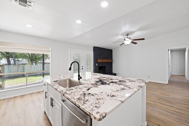 10001 Woodglen Dr, Austin, TX 78753 - kitchen featuring stainless steel dishwasher, a sink, a fireplace, light wood-type flooring, and a ceiling fan