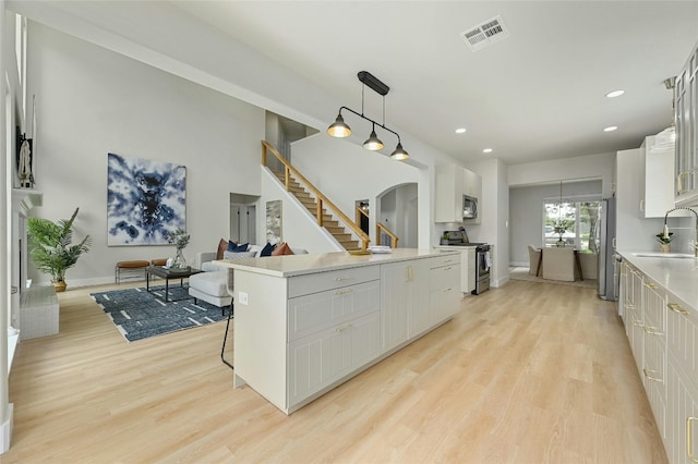 kitchen featuring light wood finished floors, visible vents, white cabinets, appliances with stainless steel finishes, and a sink