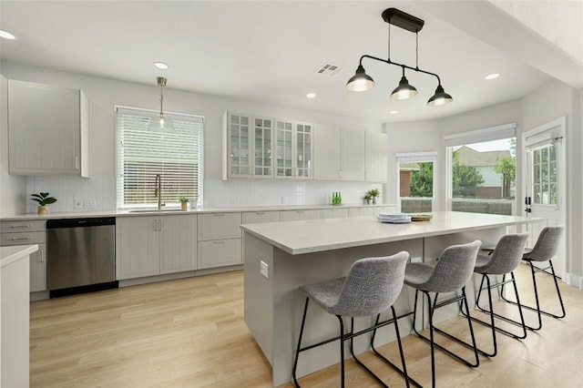 kitchen featuring decorative backsplash, visible vents, dishwasher, and a sink