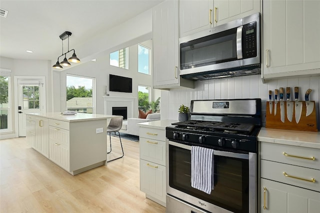 kitchen with light wood finished floors, light countertops, appliances with stainless steel finishes, and a healthy amount of sunlight