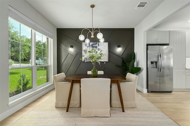 dining area featuring light wood-style flooring, plenty of natural light, visible vents, and a notable chandelier