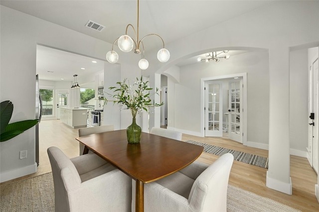 dining space featuring arched walkways, recessed lighting, visible vents, light wood-type flooring, and baseboards