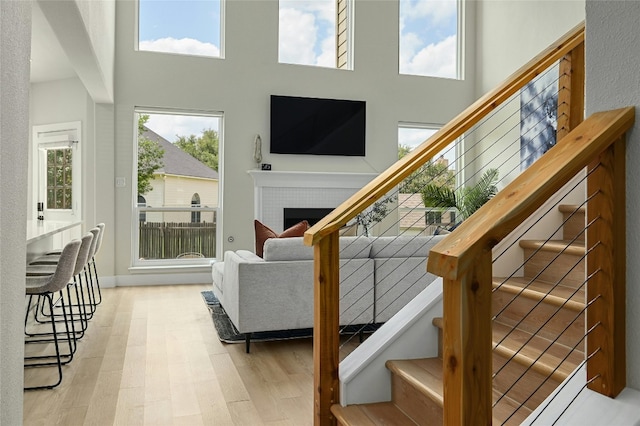 living room featuring stairway, a fireplace, wood finished floors, and a towering ceiling