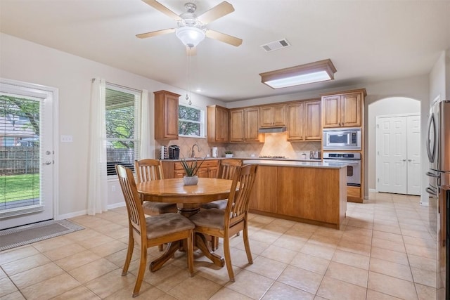 dining room featuring arched walkways, visible vents, ceiling fan, and light tile patterned floors