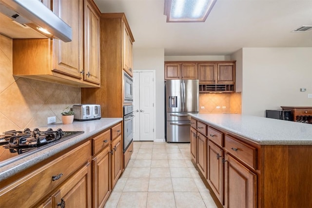 kitchen featuring stainless steel appliances, brown cabinets, visible vents, and ventilation hood