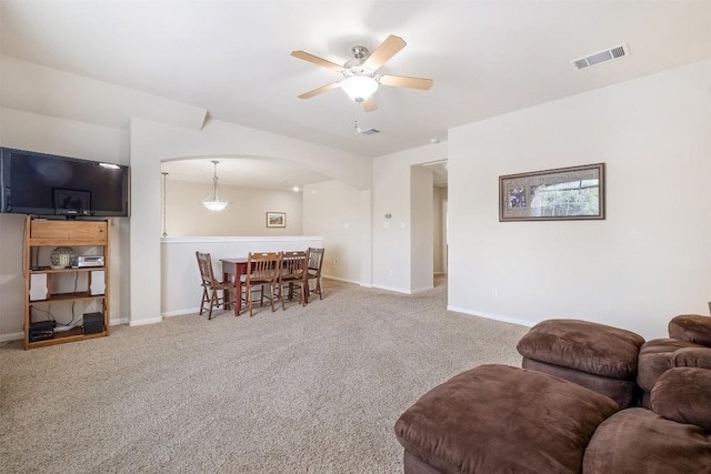 carpeted living room featuring arched walkways, visible vents, ceiling fan, and baseboards