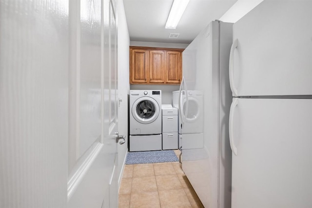 clothes washing area with light tile patterned flooring, cabinet space, and separate washer and dryer