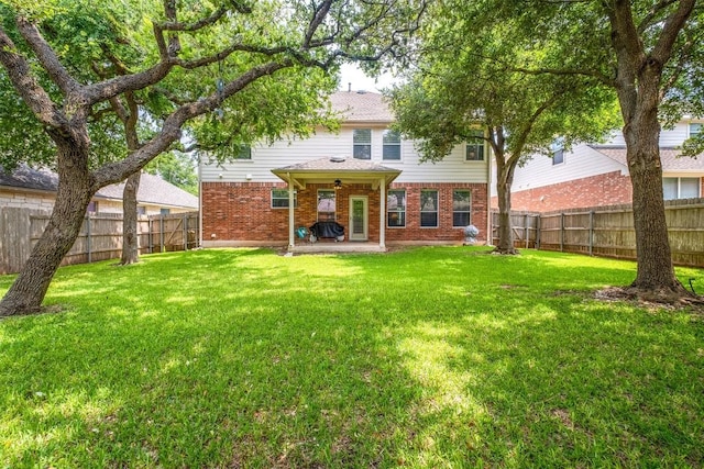 back of house with a yard, brick siding, a patio area, and a fenced backyard