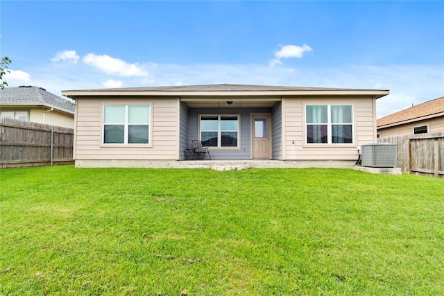 back of house with central air condition unit, a fenced backyard, and a lawn