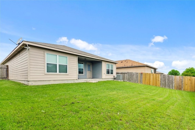 back of house with central AC unit, a lawn, and a fenced backyard