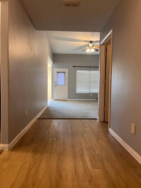 corridor with visible vents, baseboards, and wood finished floors