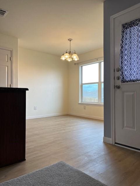 entryway featuring an inviting chandelier, light wood-style flooring, visible vents, and baseboards