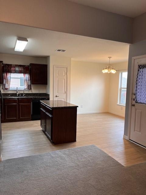 kitchen featuring a chandelier, visible vents, baseboards, dark brown cabinets, and light wood-type flooring