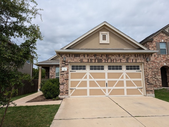 view of front facade with a garage, stucco siding, driveway, and brick siding