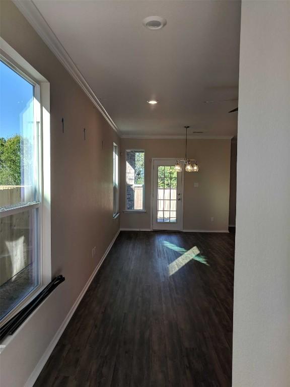 spare room with dark wood-style flooring, a notable chandelier, crown molding, recessed lighting, and baseboards