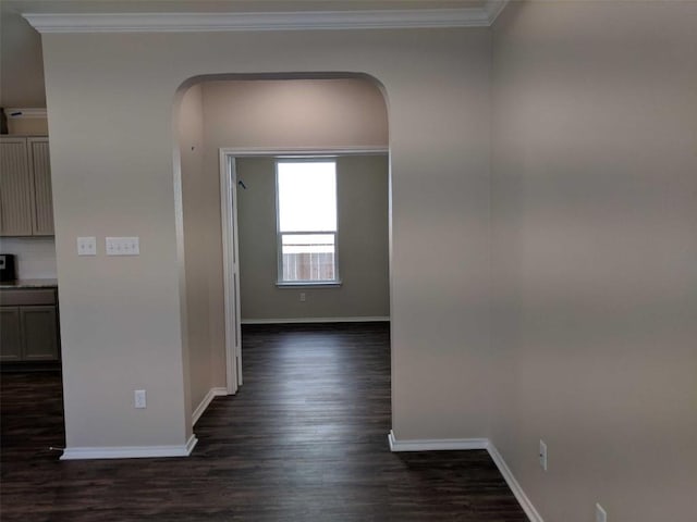 hall featuring ornamental molding, arched walkways, dark wood-style flooring, and baseboards