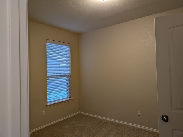 unfurnished room featuring a textured ceiling, dark colored carpet, and baseboards