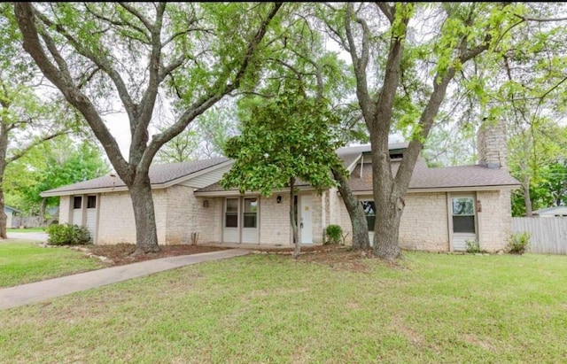 view of front of home with a chimney, fence, and a front lawn