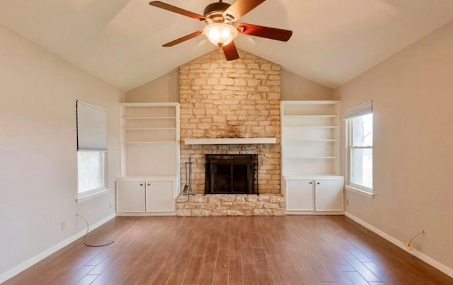 unfurnished living room with a healthy amount of sunlight, a fireplace, built in features, and wood finished floors