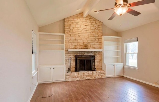 unfurnished living room featuring vaulted ceiling with beams, a stone fireplace, wood finished floors, a ceiling fan, and baseboards