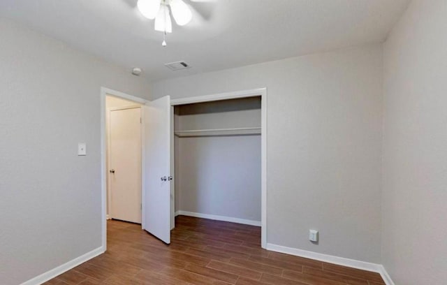 unfurnished bedroom featuring a closet, visible vents, ceiling fan, wood finished floors, and baseboards