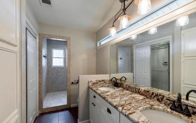 bathroom with wood finished floors, visible vents, a sink, and a walk in shower