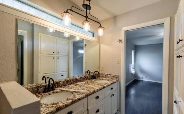 bathroom featuring double vanity, a sink, baseboards, and wood finished floors