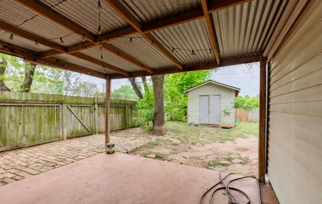 view of patio / terrace featuring a shed, fence, and an outbuilding