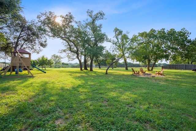 view of yard featuring an outdoor fire pit, a playground, and fence