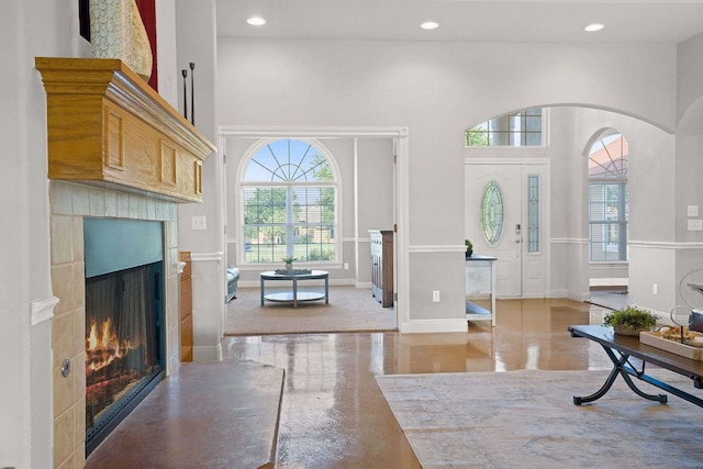 foyer with arched walkways, a lit fireplace, a towering ceiling, and recessed lighting